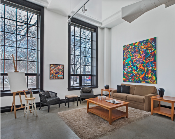 Interior photo of living room of the Artspace Lofts with large painting on the wall and floor to ceiling windows.