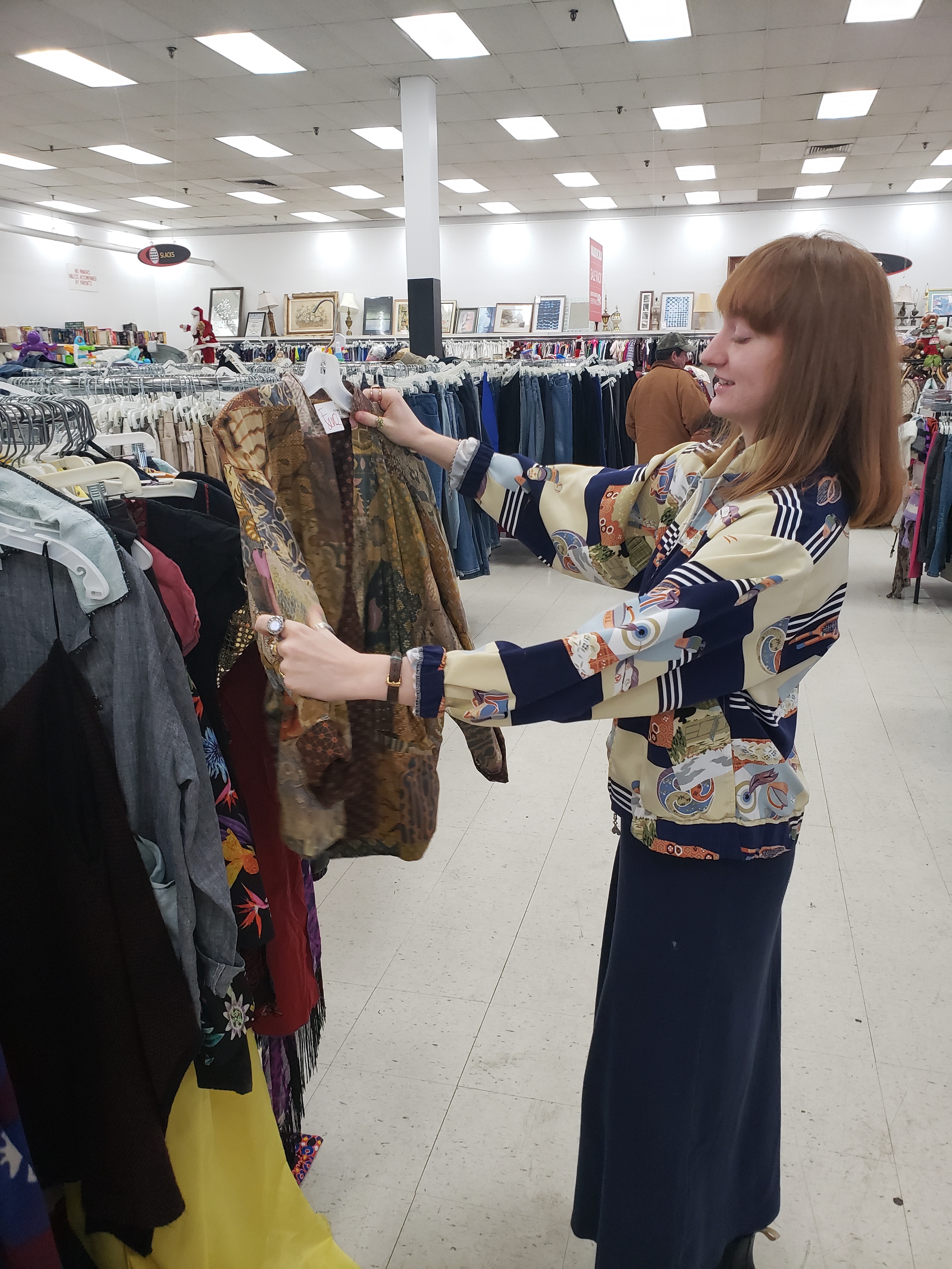 Photo shows Olivia Grantham browsing clothing racks at a thrift store