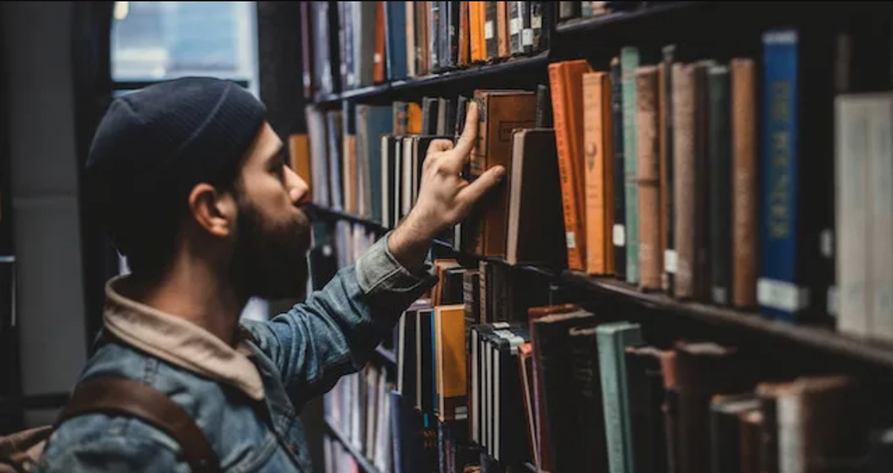 Photo of man looking for a book. Courtesy BookRiot.com
