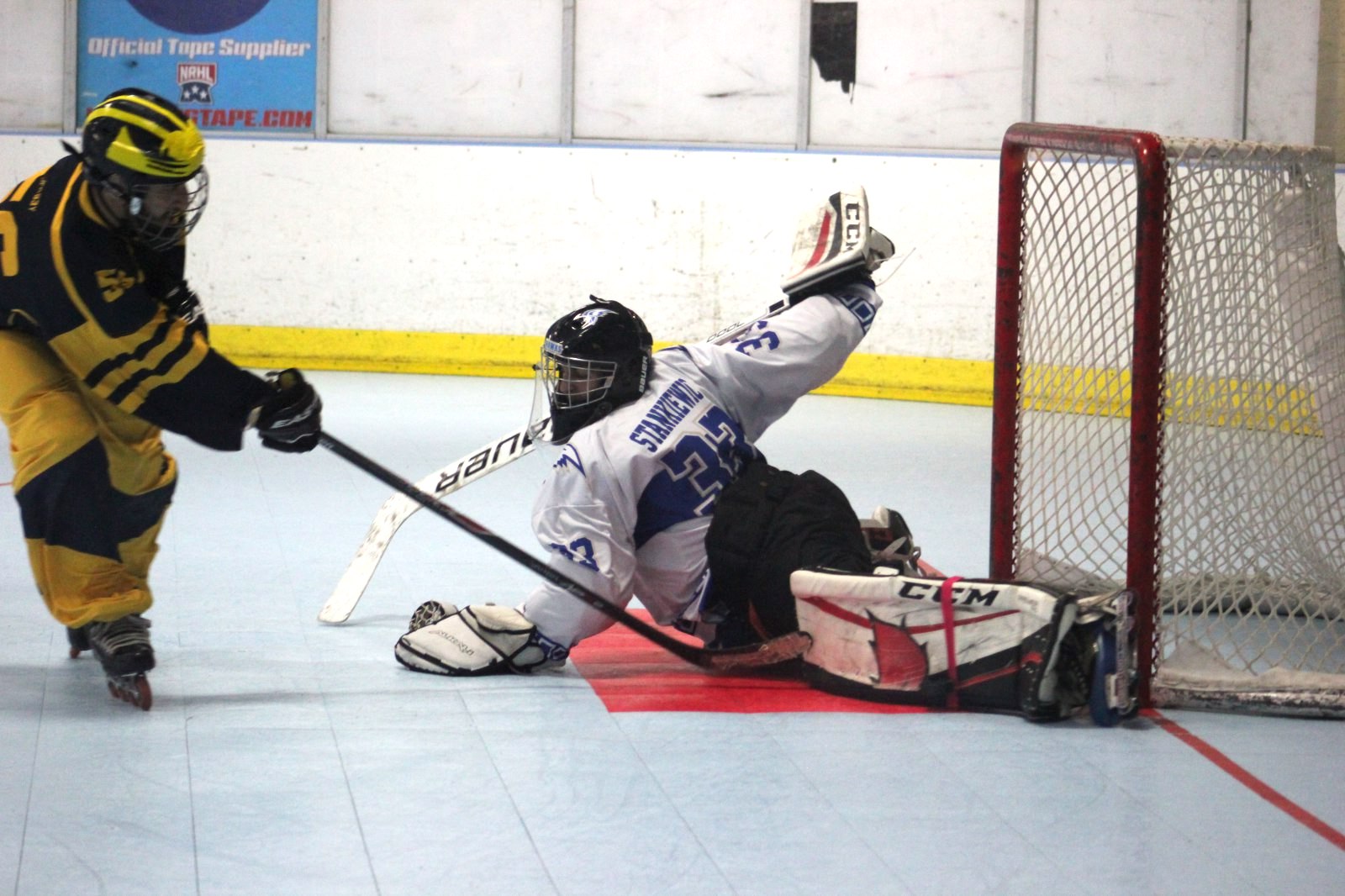 Goalie doing splits to stop goal.