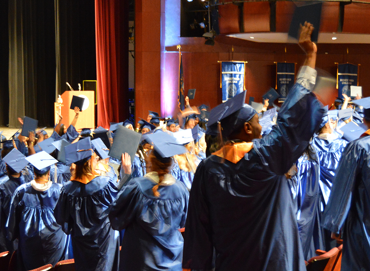 Students wearing the graduation caps in the graduating ceremony facing the stage.