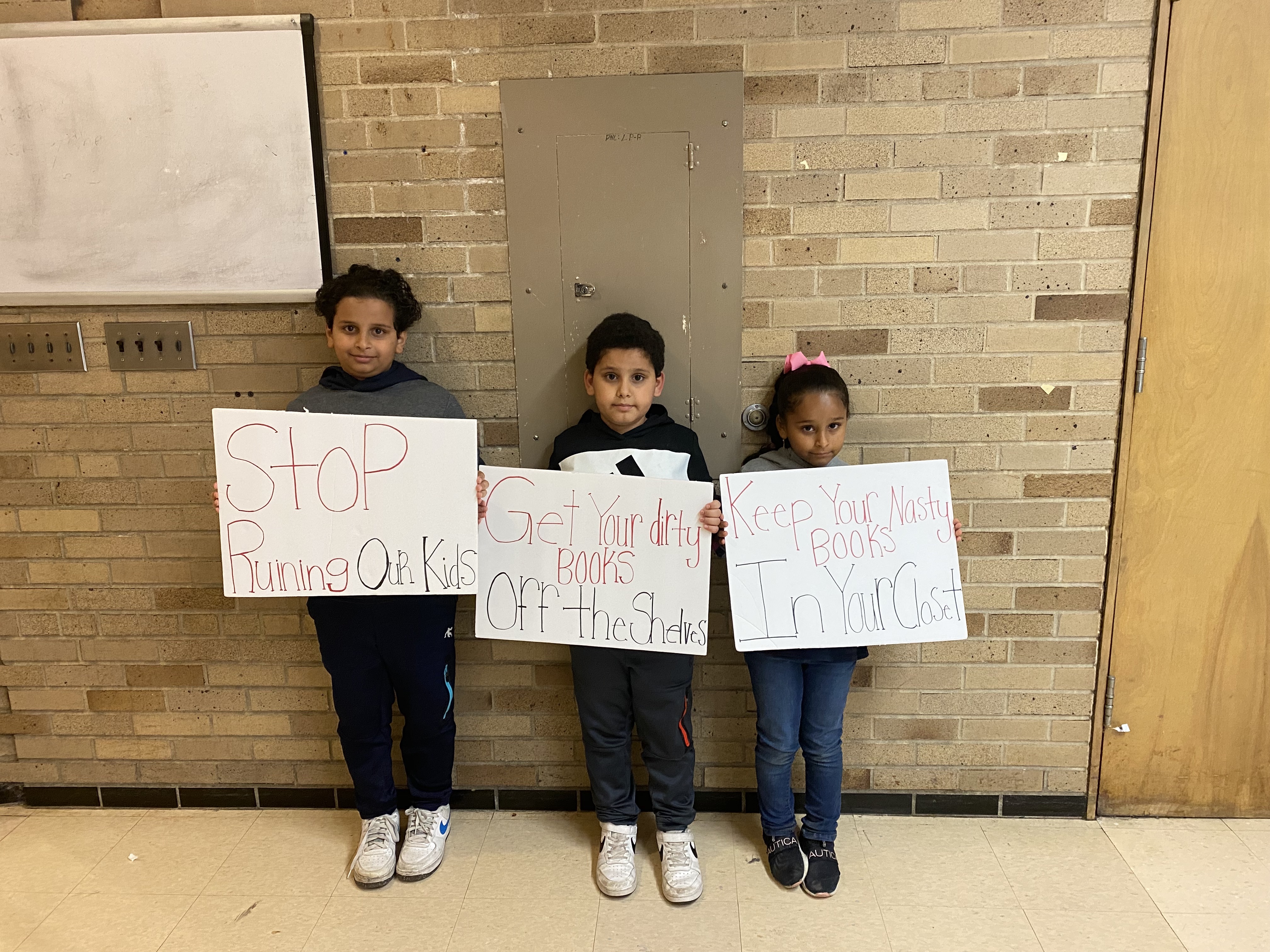 Jaber children holding signs at Dearborn School Board meeting Oct. 14, 2022 Stout Middle School Dearborn, MI photo by Aliyah Mansour