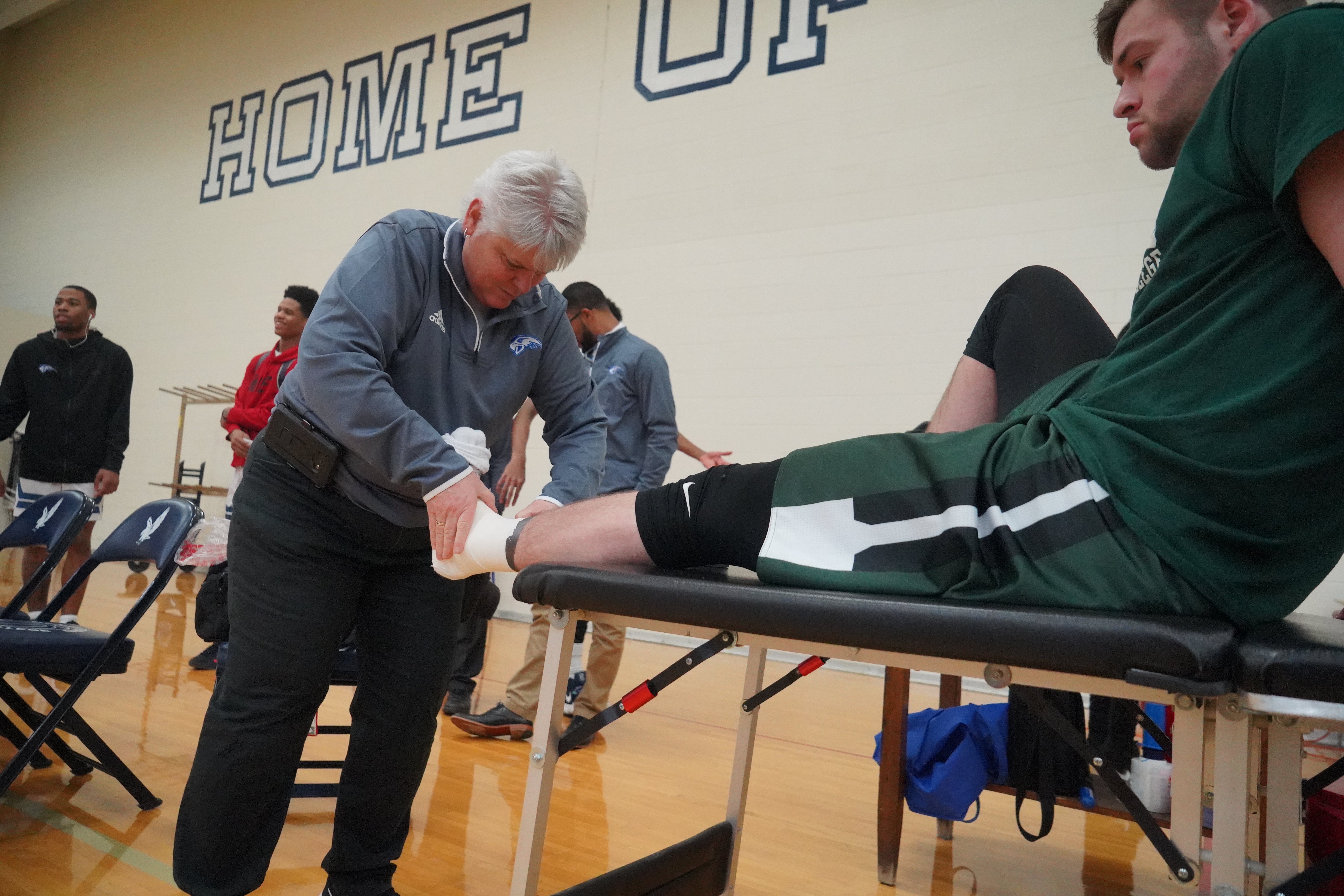 Jan Lauer HFC Athletic Trainer tending to athlete in gym, Henry Ford College main campus, Dearborn, MI photo courtesy Hawks Athletics