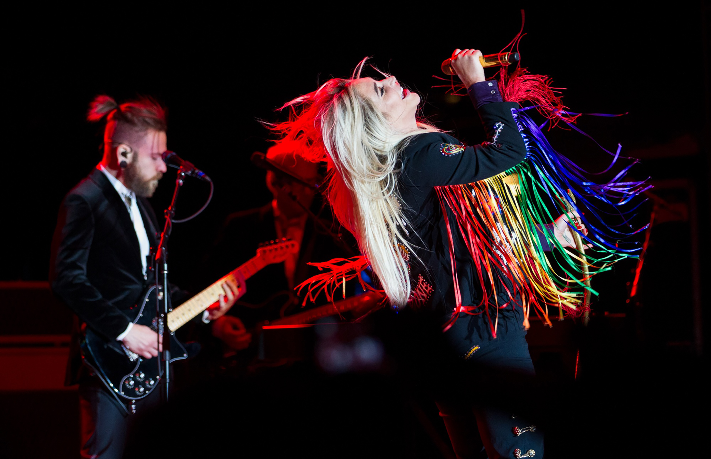 Image of Kesha performing and a guitar player behind her