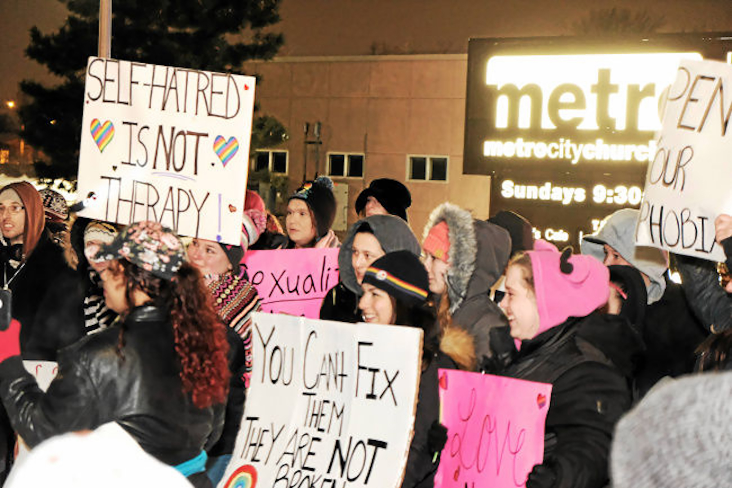 Group of women protesting and holding posters against conversion therapy.