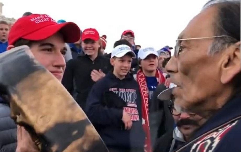 Nathan Phillips in Native American apparel and crowd of students wearing Make America Great Again hats and sweatshirts at Washington D.C. mall, Jan. 18, 2019