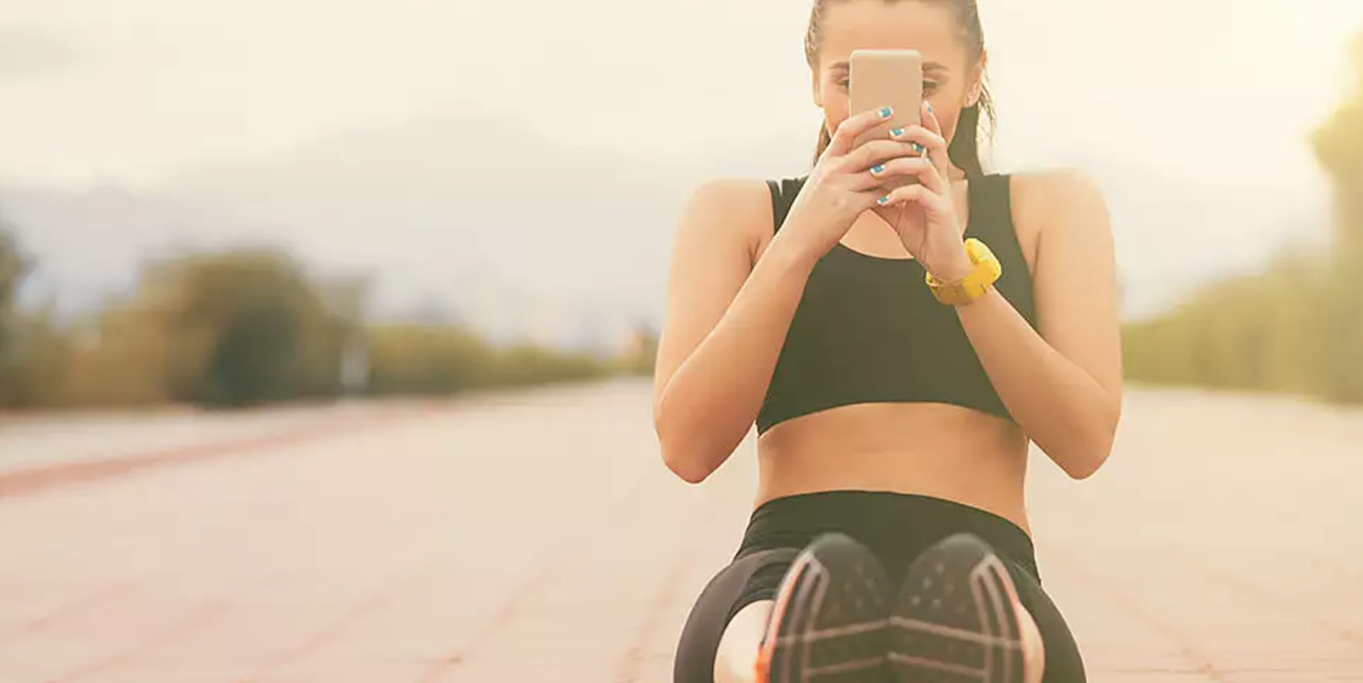 Young woman in exercise clothes on track looking at phone. Photo by muratdeniz - Getty Images