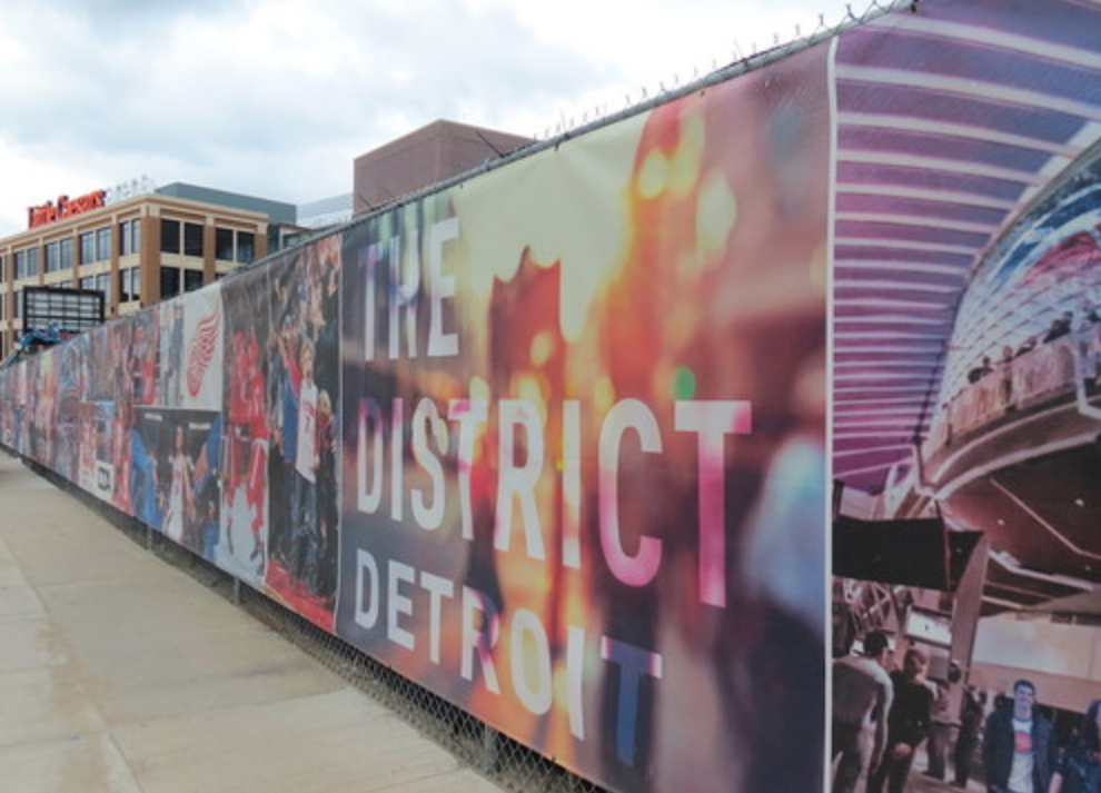 Image of gates covered with ads regarding "District Detroit."