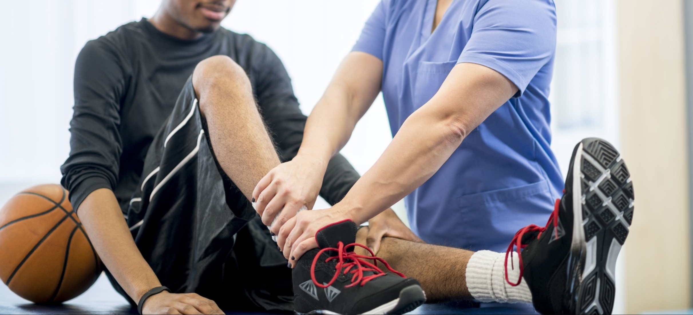 Image shows an athletic trainer working on an athlete 