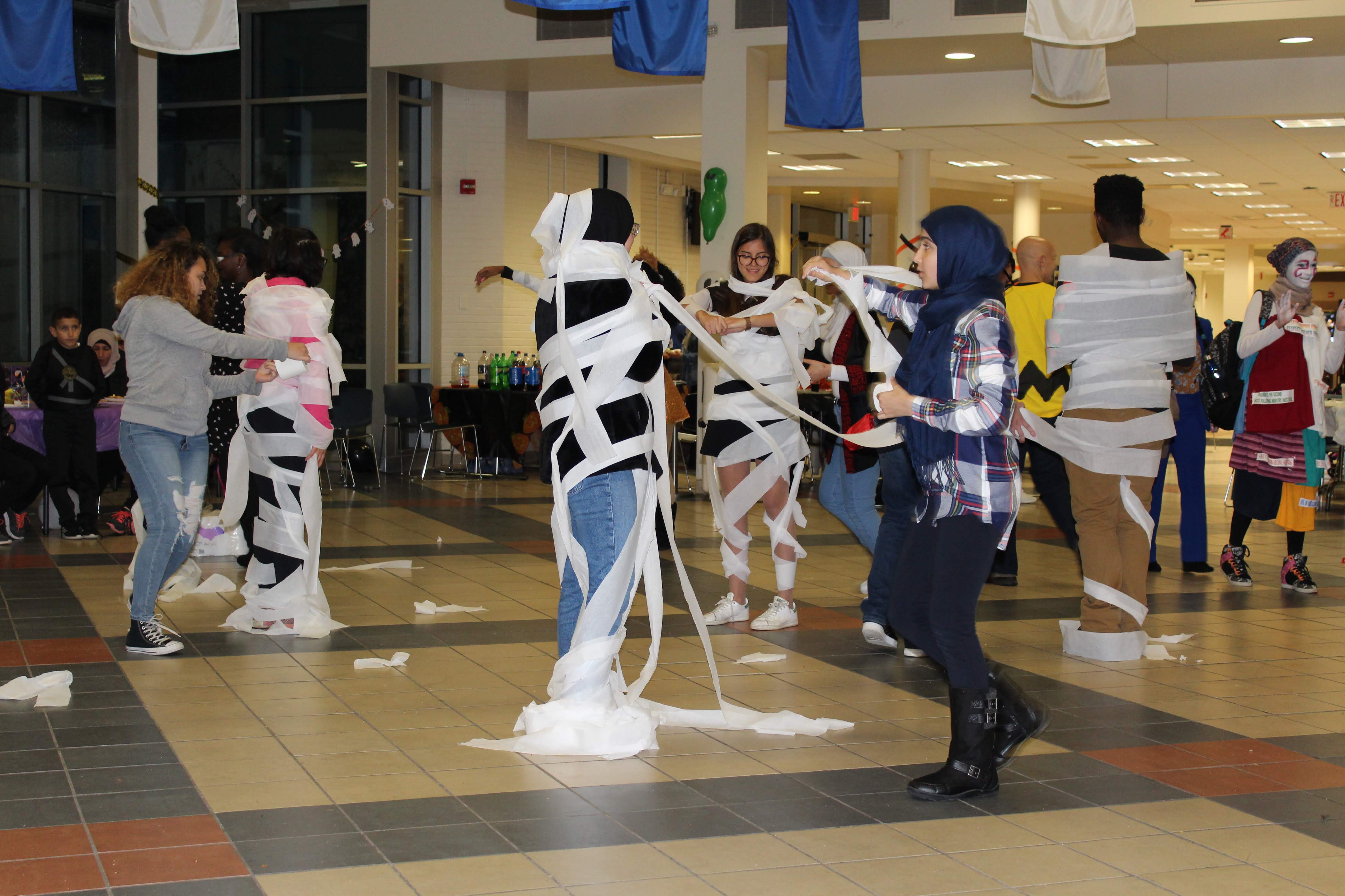 Photo shows students being wrapped up like mummies representing "walking debt"