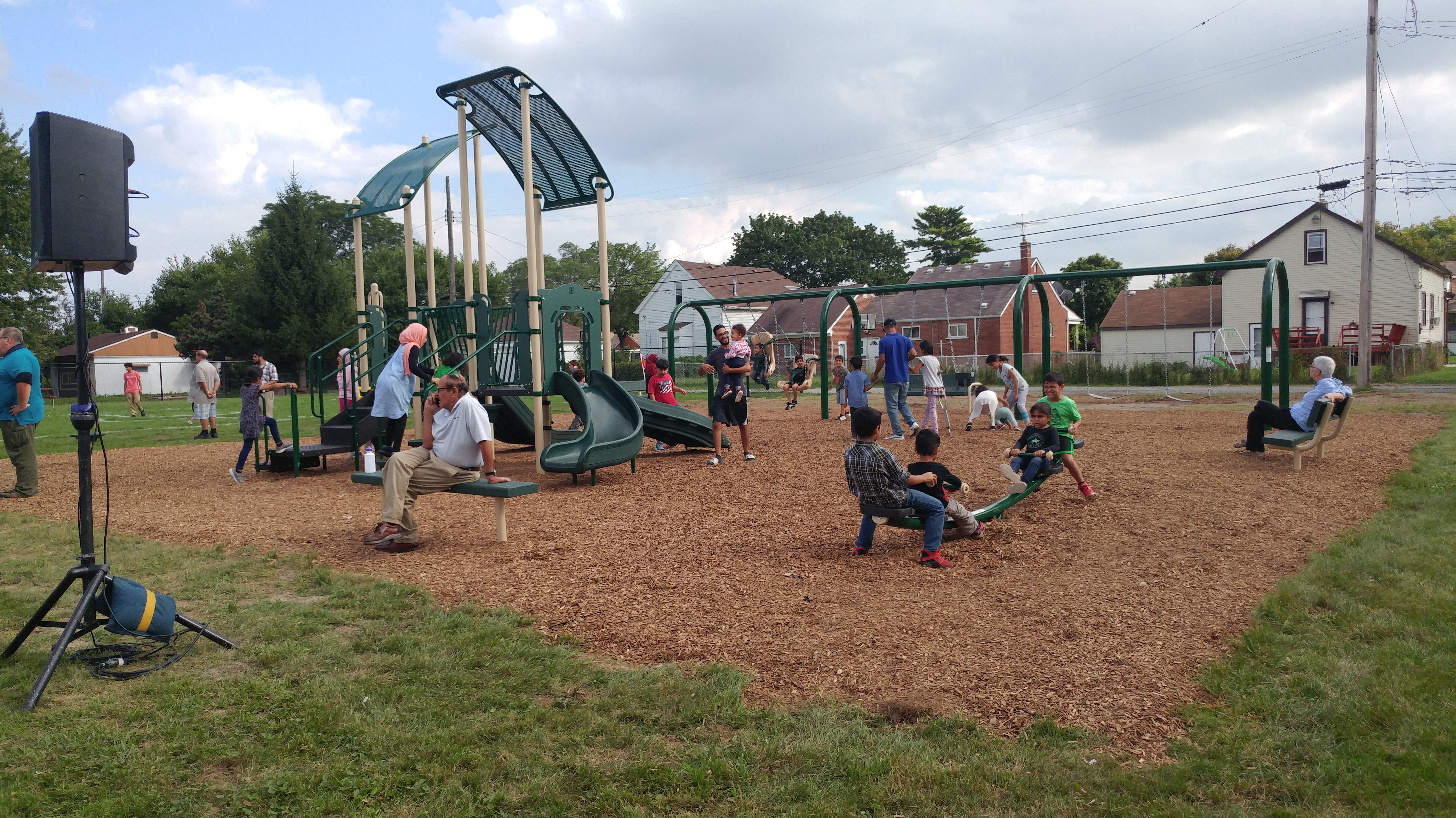 Image of Graham Street Park, showing several children enjoying a play structure, swing set and see-saw
