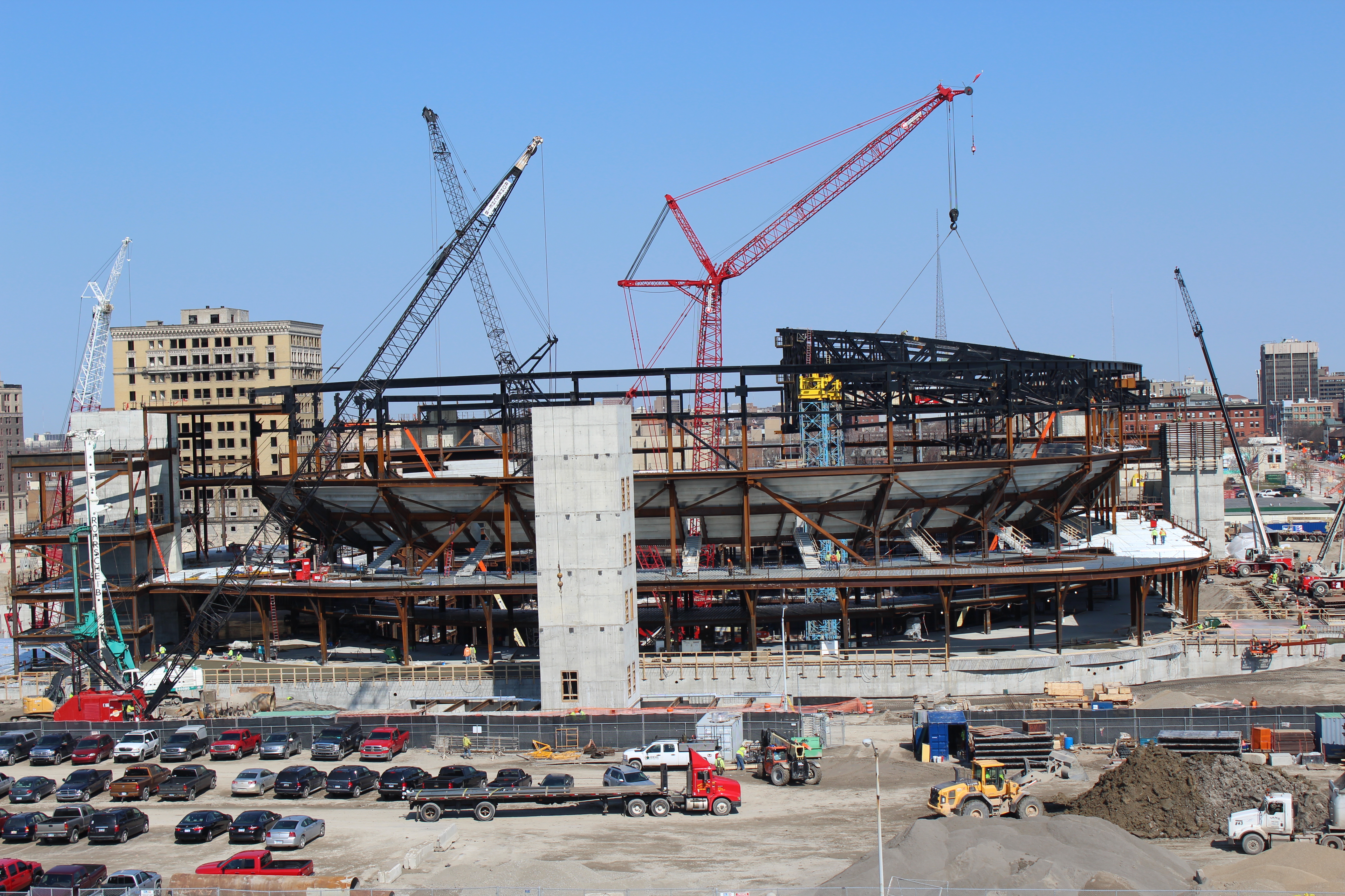 Photo of construction of Little Caesars Arena showing the metal frame of the arena is nearly complete.