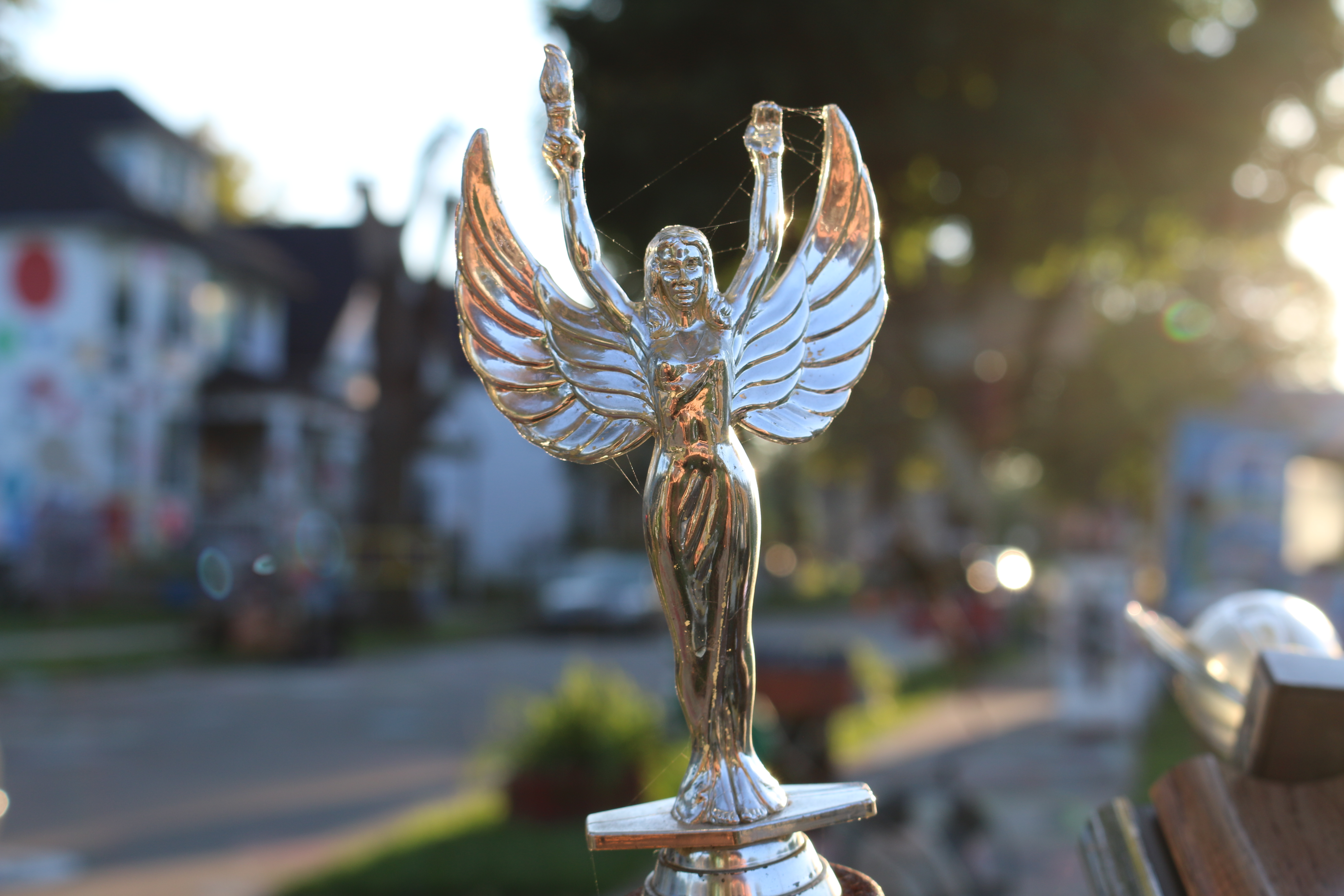 Close up of gold hood ornament of woman with wings.