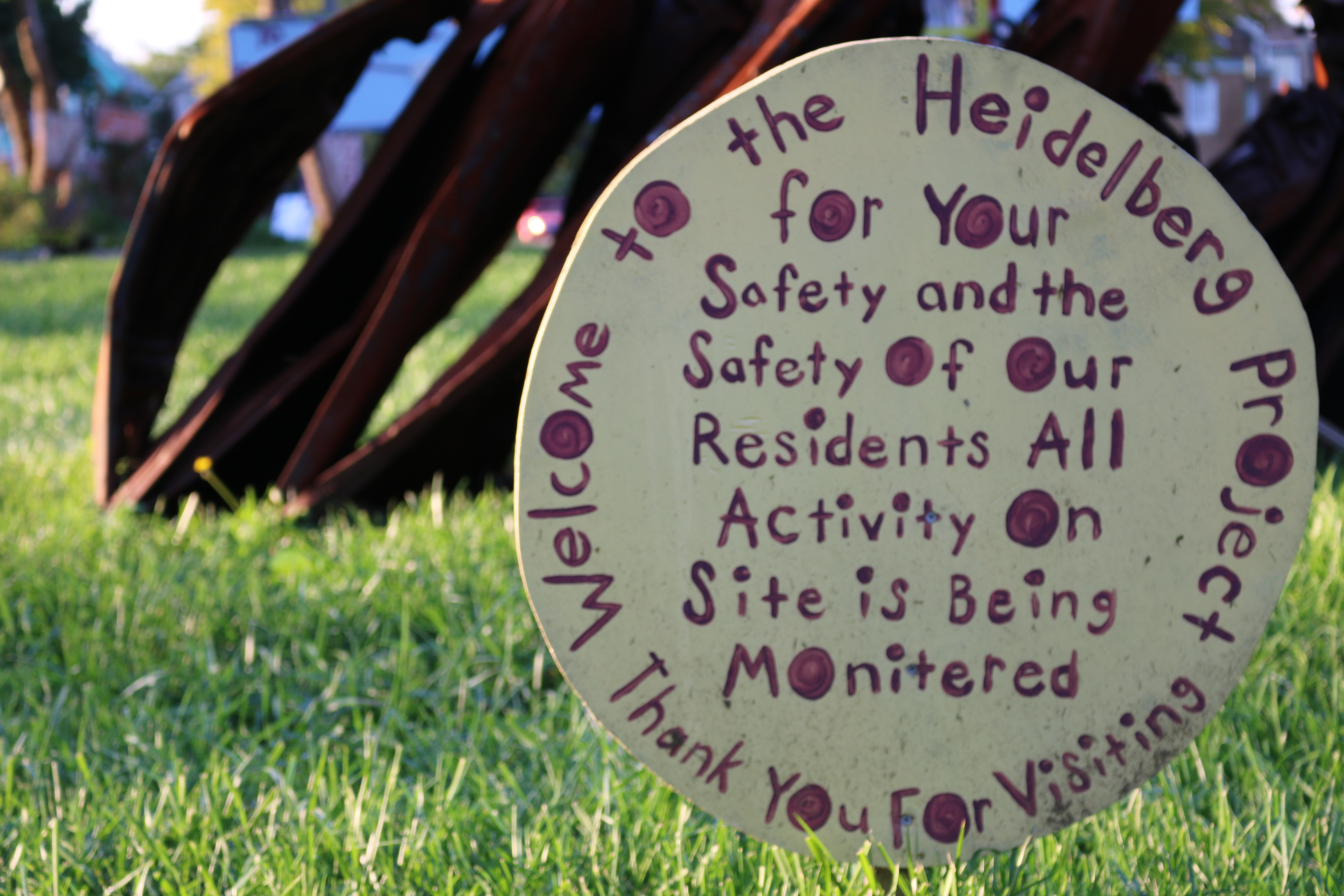 Close up of circular sign stating Heidelberg Project is being monitored for everyone's safety.