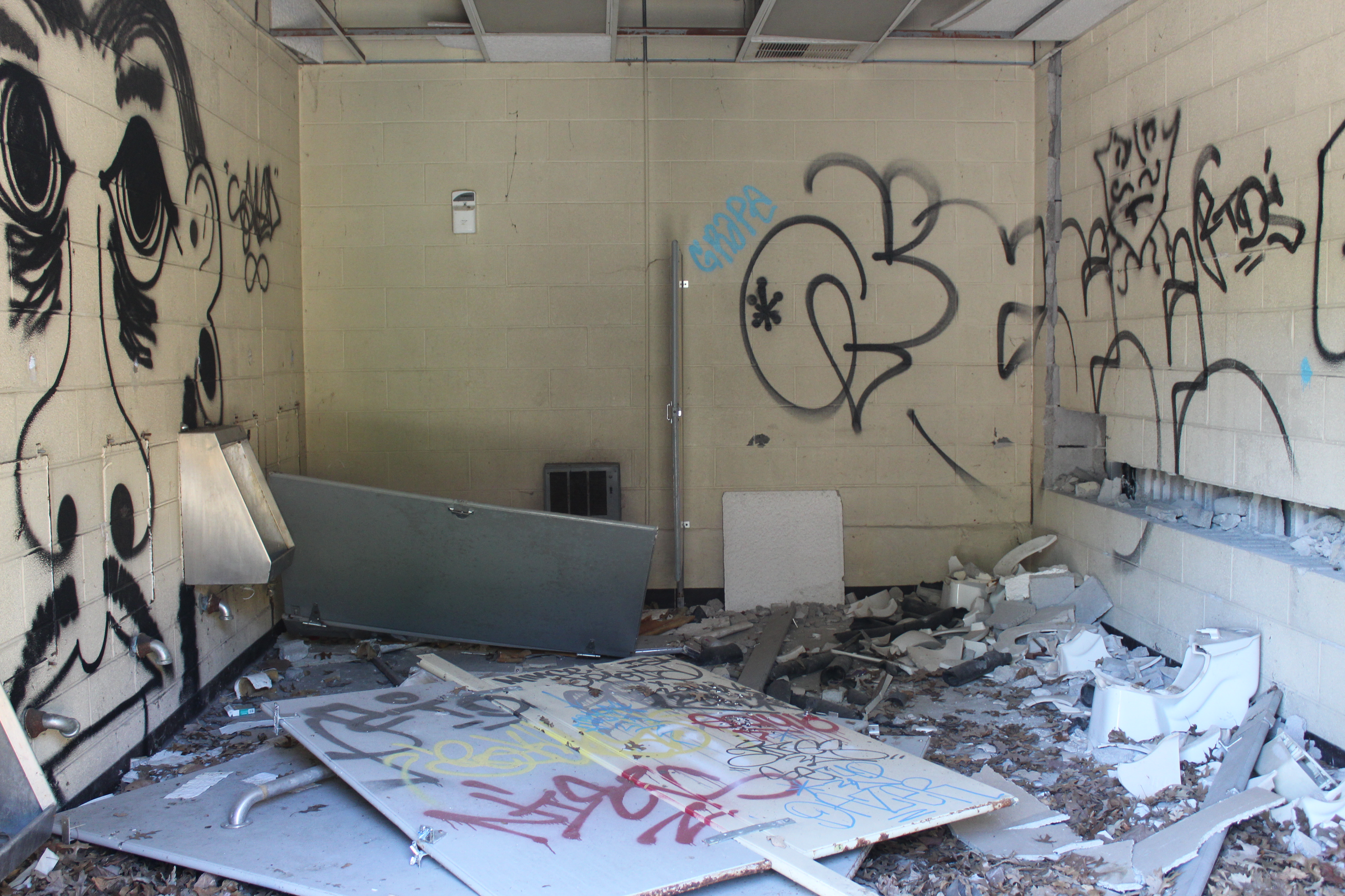 Abandoned and graffiti filled restroom at Belle Isle Zoo with smashed sinks and toilets.