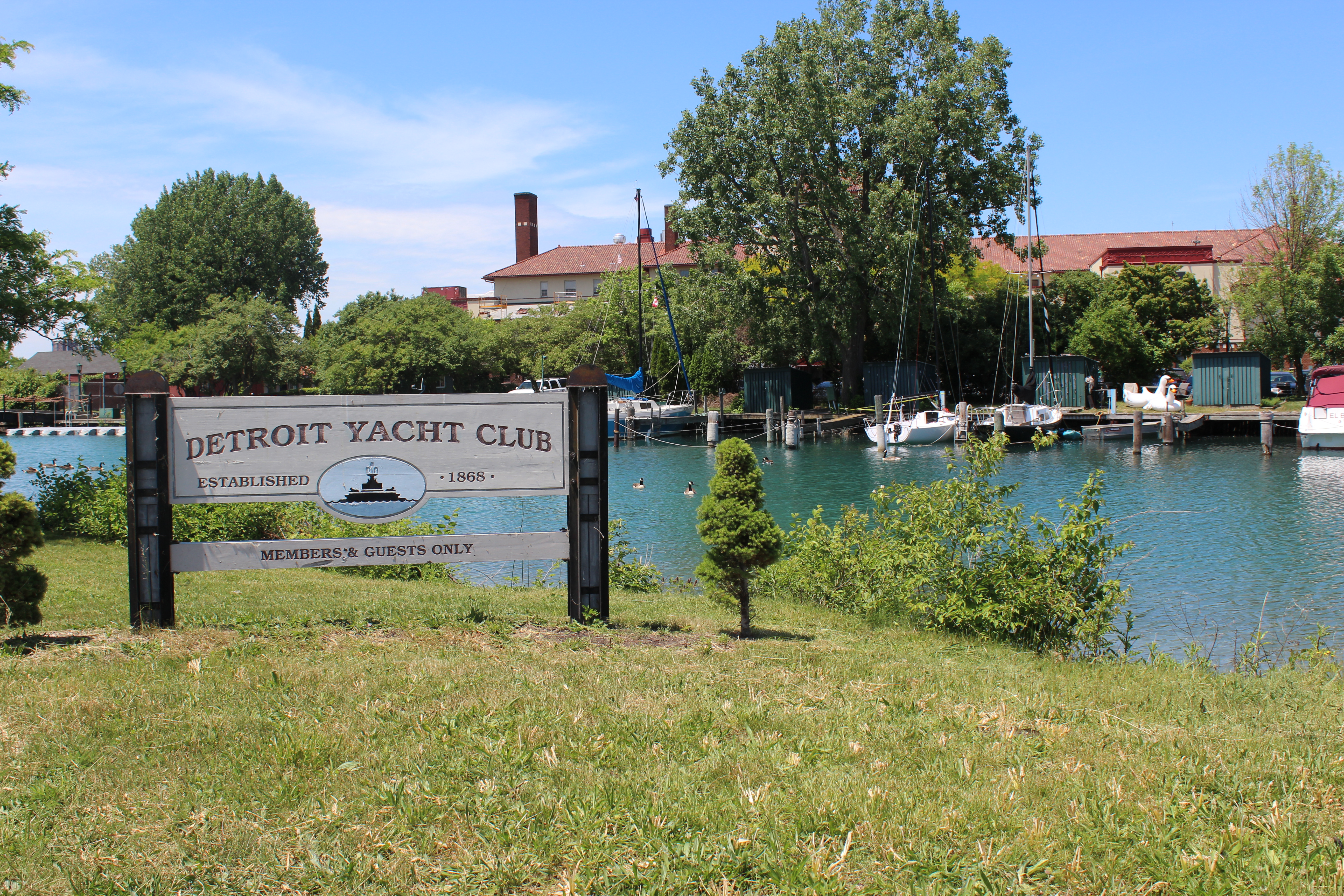 Detroit Yacht Club sign with sail boats on the dock behind it