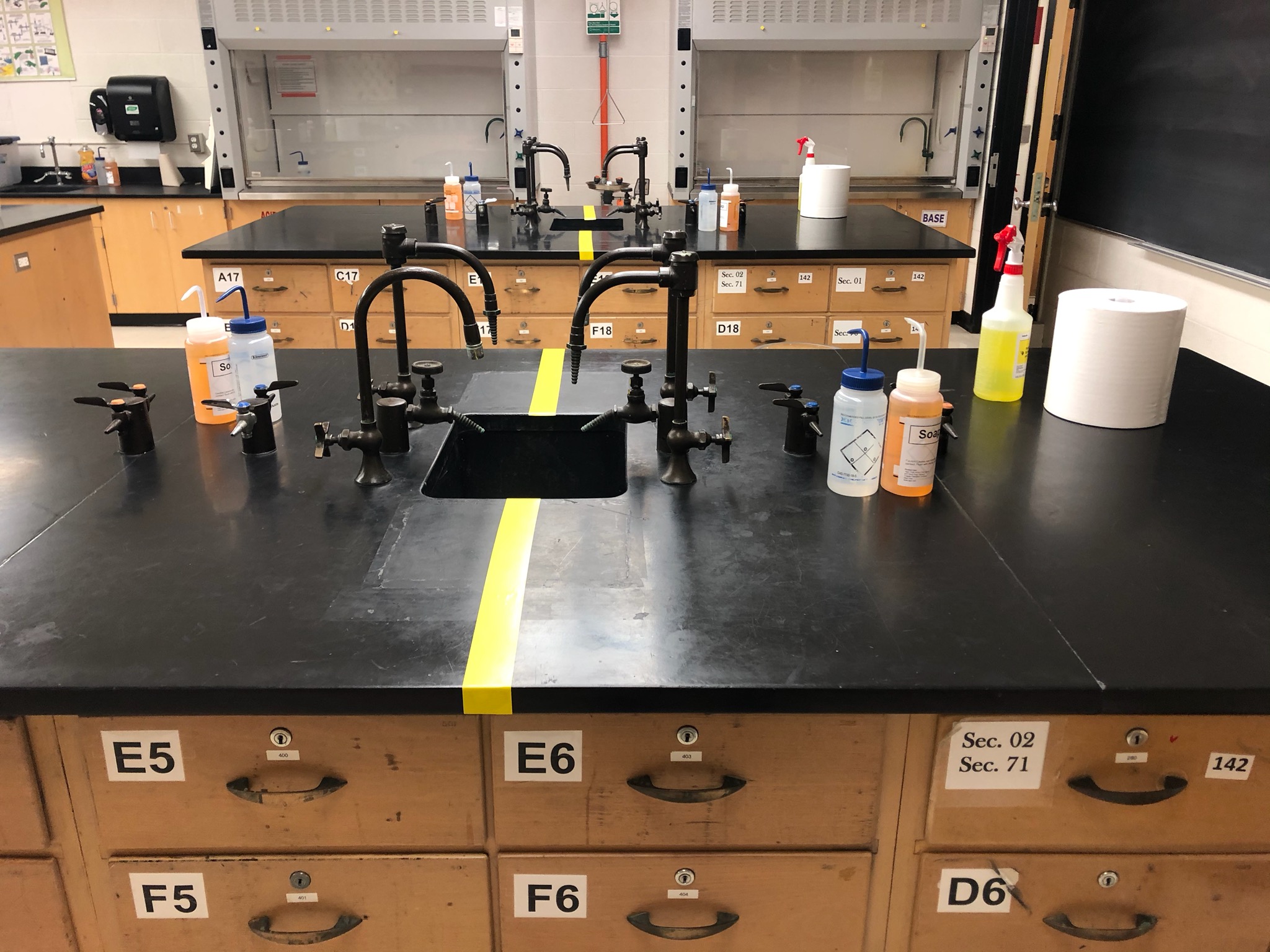 Organic chemistry bench tops sectioned by yellow tape. Every student is provided their own deionized water and soap bottles. Only essential items for each lab are placed at every student station. Photo taken by Ms. Alice Hull