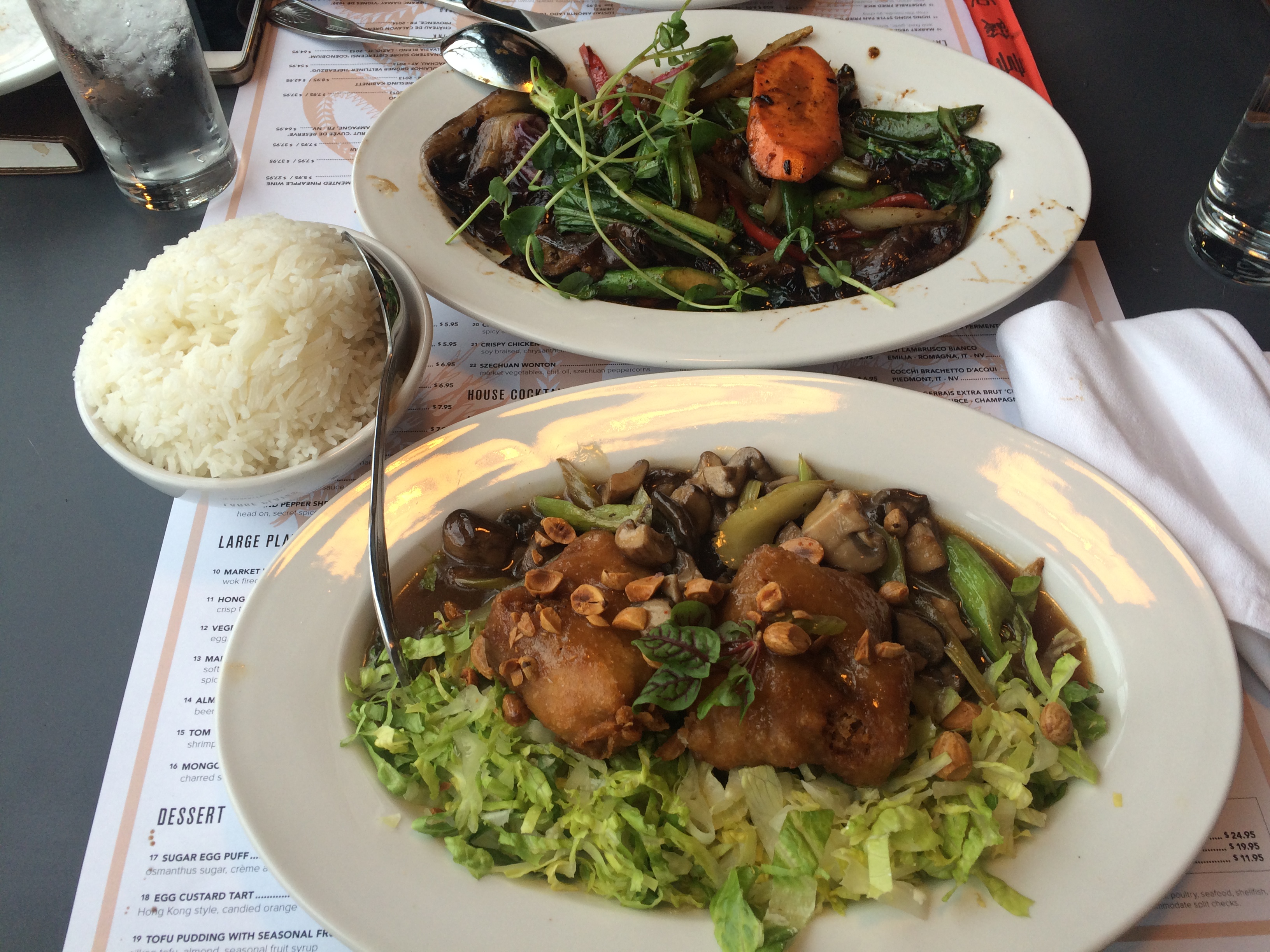 An Asian meal, with meats, veggies, and rice, sits on a table.