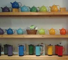 Several colorful teapots sit on a shelf in Socra-tea.