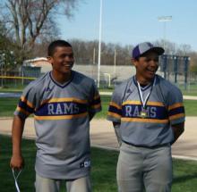 Two men pose for a photo, smiling, wearing baseball uniforms.