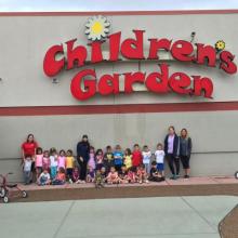 Image of a group of people and children standing outside of Children's Garden daycare