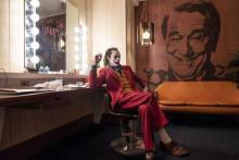 Photo shows Joaquin Phoenix as "Joker" sitting in a dressing room near a mural of Robert De Niro