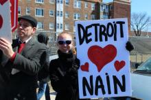 A man marching with the mache du nain holding a sign that says Detroit heart Nain