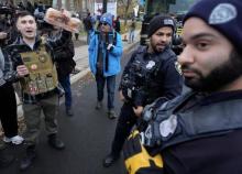 Members of the Dearborn police department watch over a protest as anti muslim activist Jake Lang left holds a pound of bacon in Dearborn  