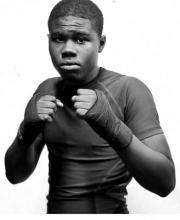 A young black man with his fists up. His fists are wrapped with fabric.
