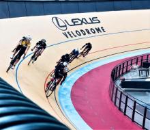 Seven cyclers racing at the Lexus Velodrome cycling track.