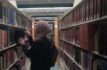 Student looking for book at Henry Ford College Eshleman Library courtesy HFC Marketing