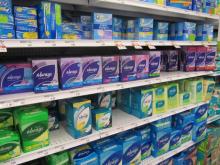 Rows of various brands of tampon boxes on a store shelf.